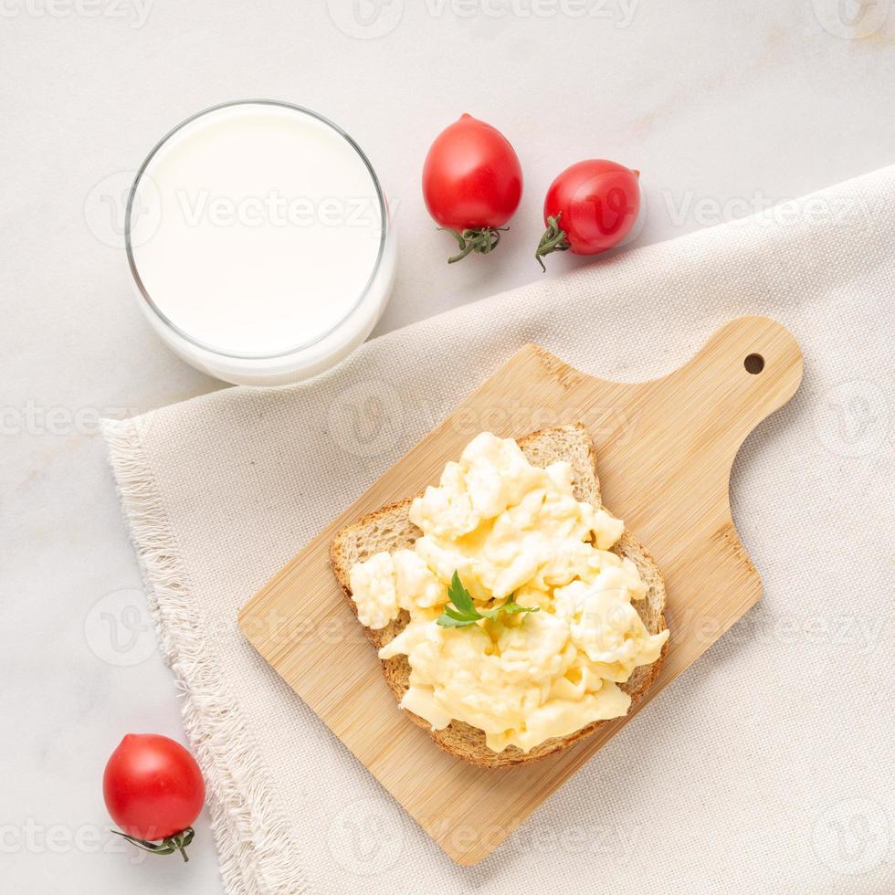 sándwich con huevos revueltos fritos en una tabla de cortar de madera, vista superior. foto