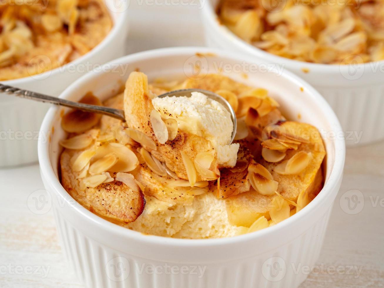 Cheesecake on white wooden table in kitchen. Delicate curd dessert with apples, almond flakes photo