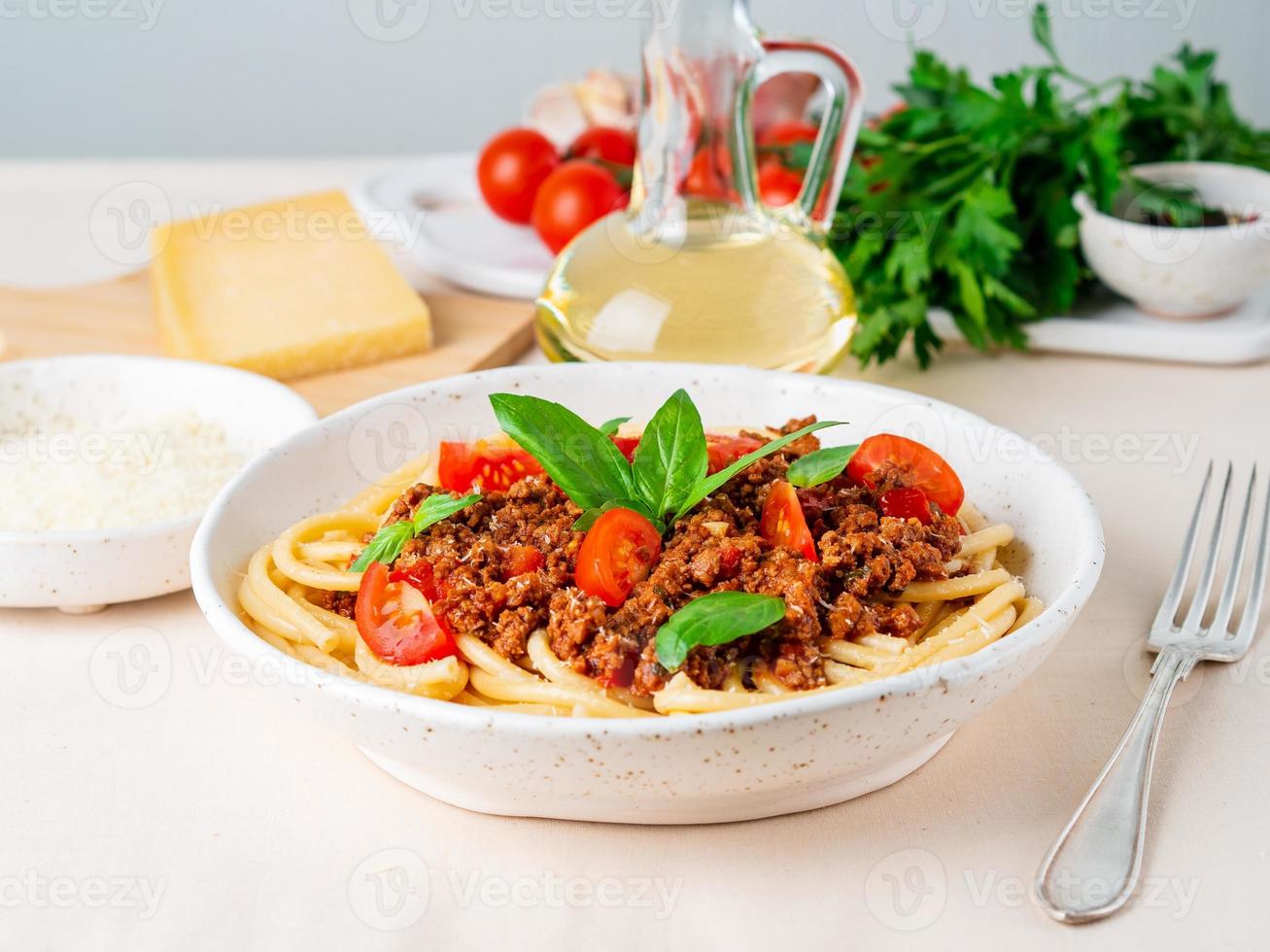 pasta bolognese with tomato sauce, ground minced beef, basil leaves on background photo