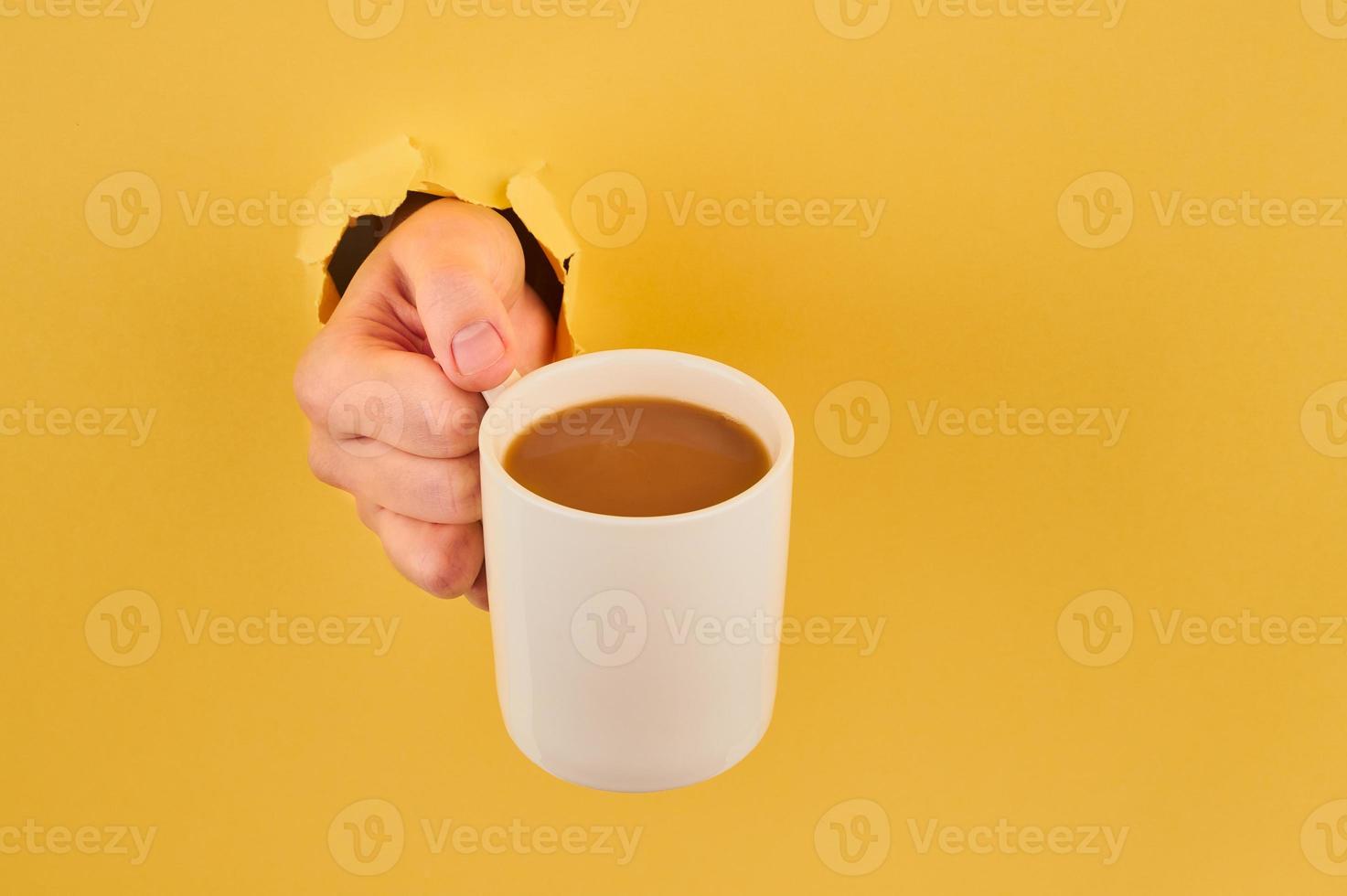 Unrecognizable person holding coffee mug on orange background, copy space closeup photo
