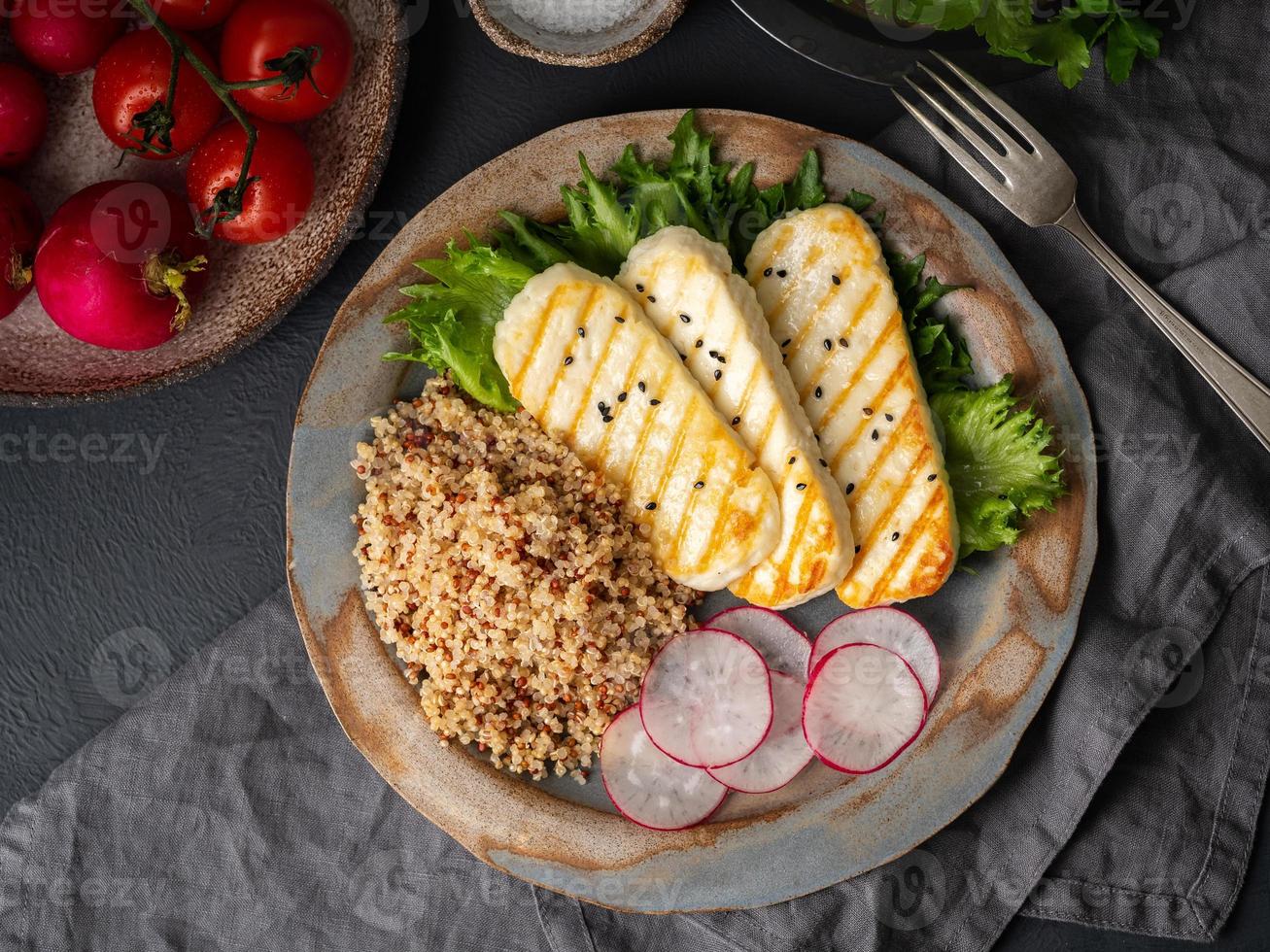 Halloumi, grilled cheese with quinoa, salad, radish. Balanced diet on dark background, top view photo