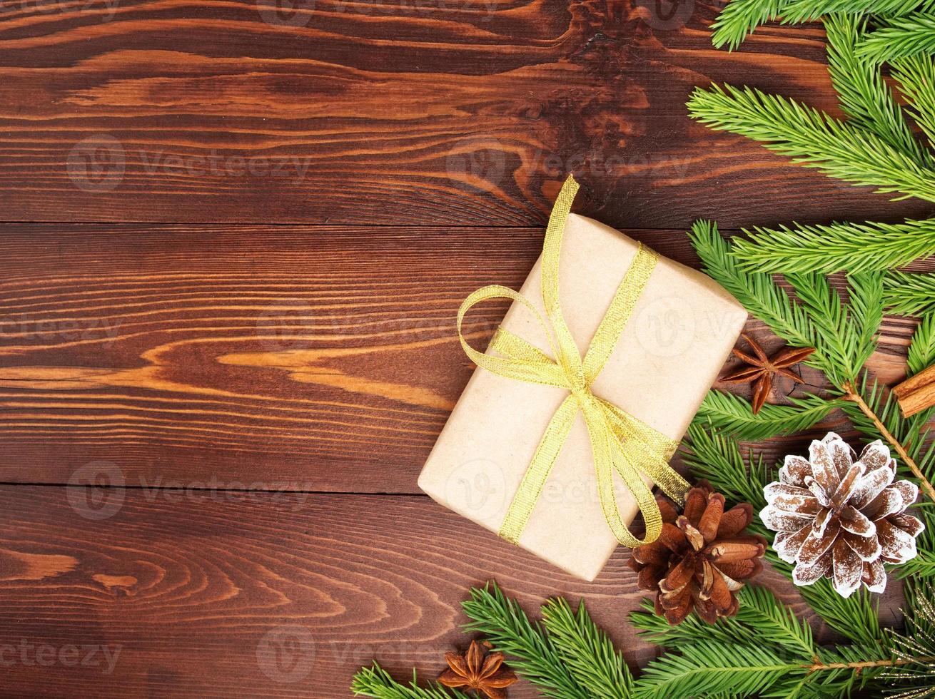 navidad y feliz año nuevo fondo marrón oscuro. caja de regalo de navidad, ramas de abeto, mesa de madera, vista superior, espacio de copia foto