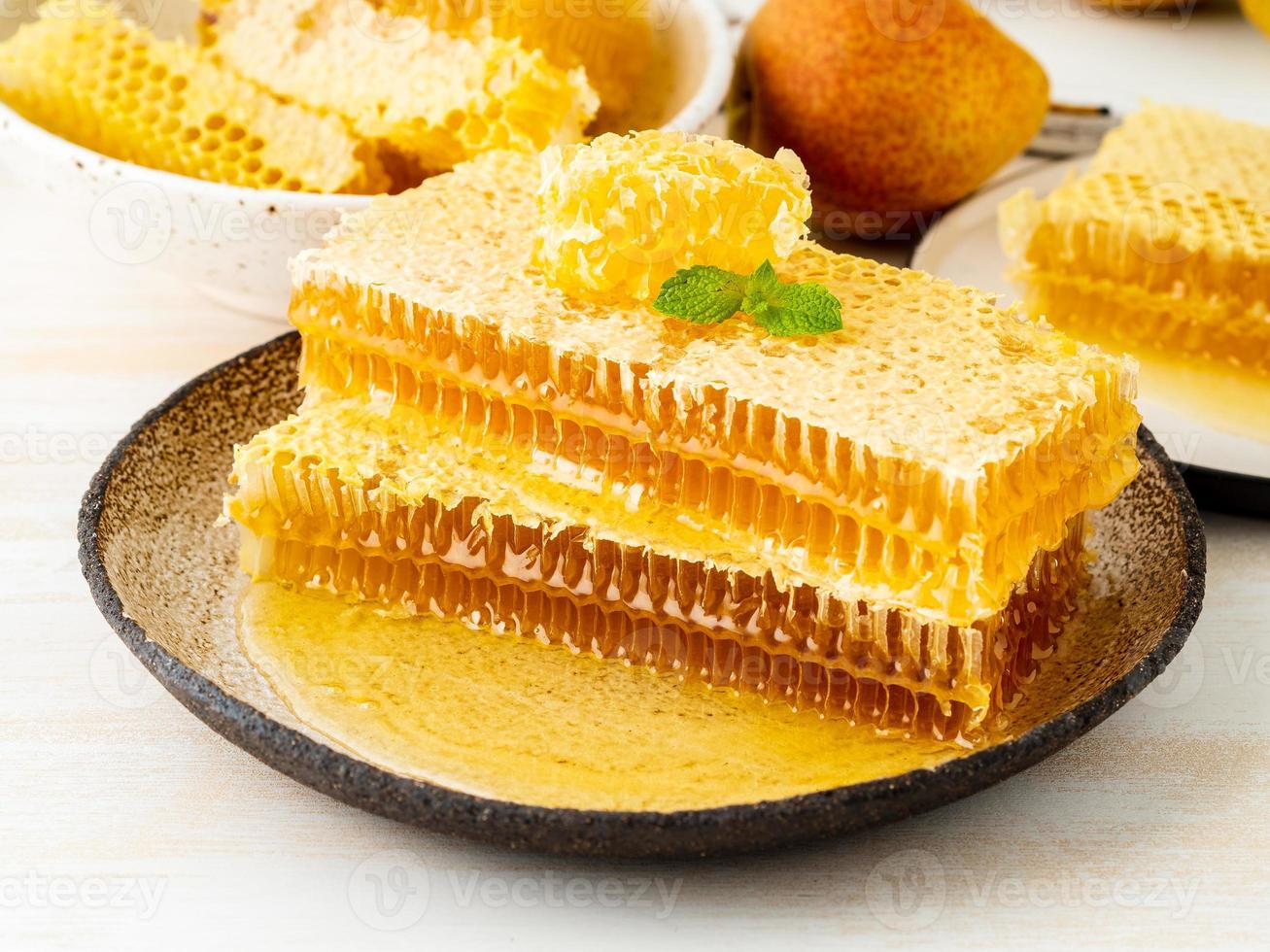 honey in honeycomb, close-up, on brown ceramic plate, on white wooden rustic table, side view photo
