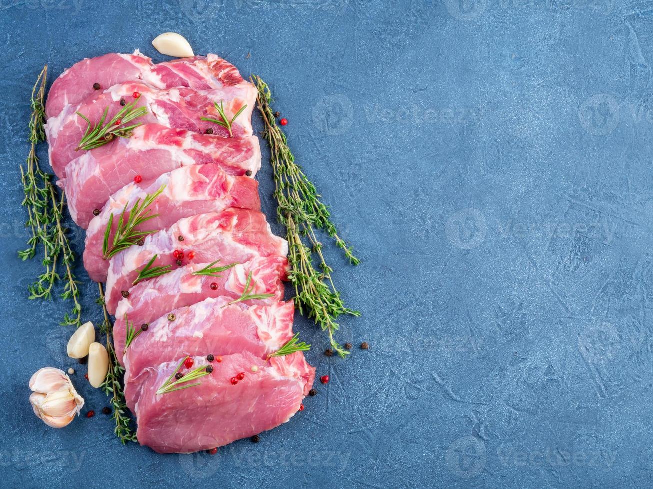 Pork steak, raw carbonate fillet on dark background, meat with seasonings, top view, copy space photo