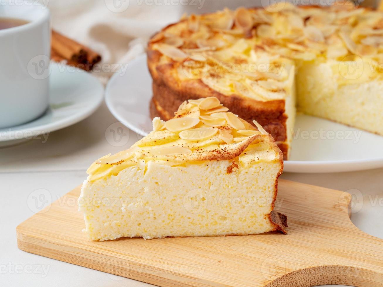 tarta de queso, tarta de manzana, postre de cuajada con polenta, manzanas, copos de almendras y canela en la mesa de la cocina de mármol blanco, vista lateral foto