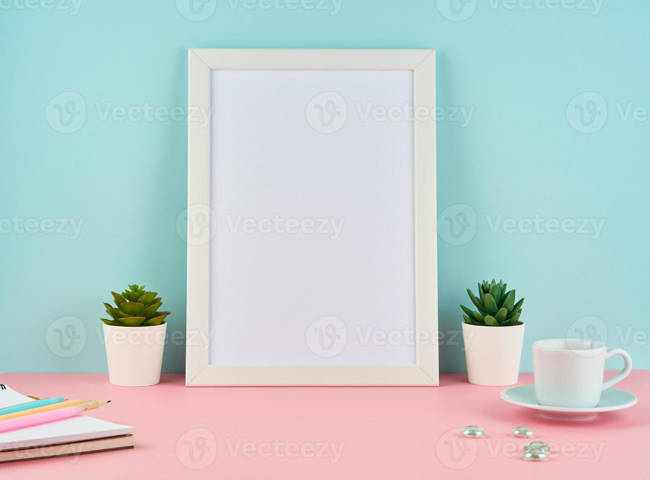 Mockup with blank white frame, plant cactus, cup of coffee or tea on pink table photo