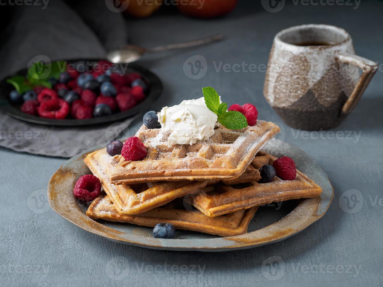 Belgian waffles with raspberries, chocolate syrup. Breakfast with tea on dark background, side view photo