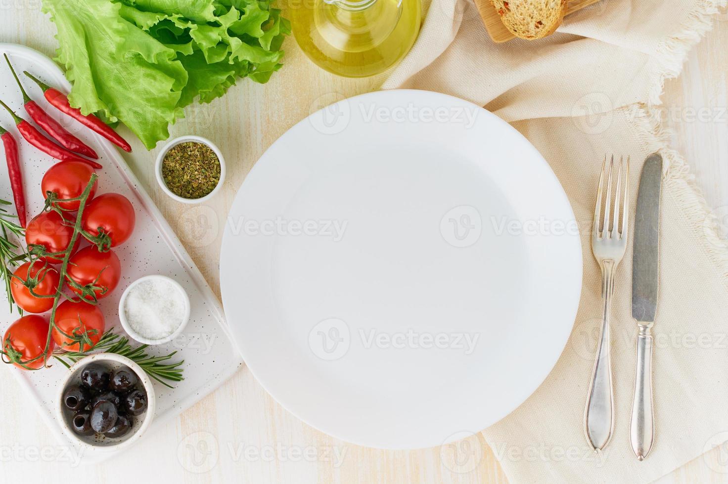 clean empty white plate and vegetables on beige wooden background, top view, copy space photo