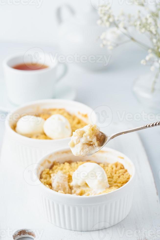 Apple crumble, spoon with ice cream, streusel. Side view, vertical. Morning breakfast photo