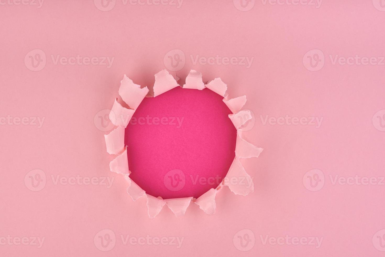 A ripped hole in pink textured background, concept of rupted paper photo