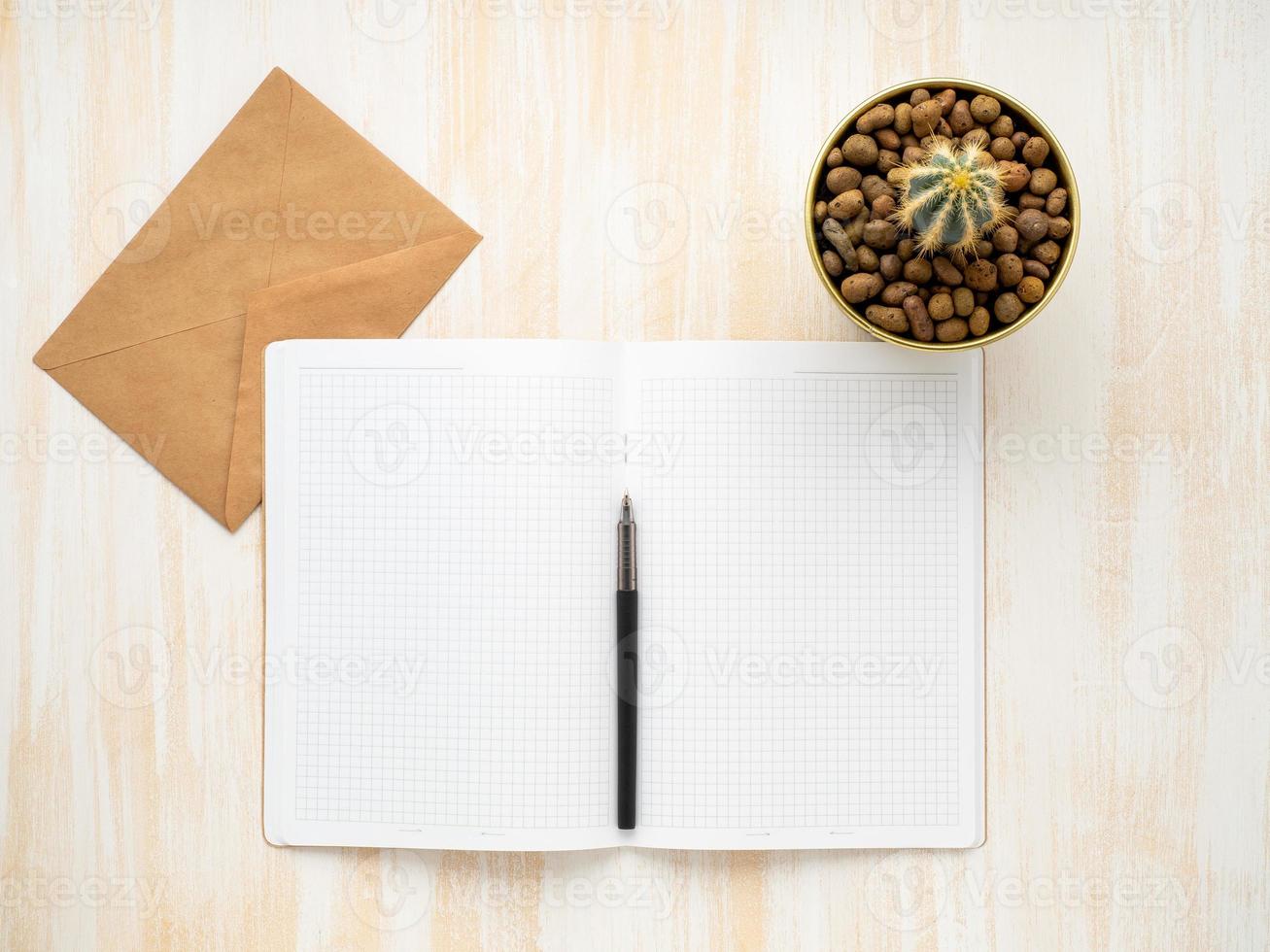 white open notepad, kraft envelope and cactus in pot lying on beige wooden desk, flat lay, copyspace photo