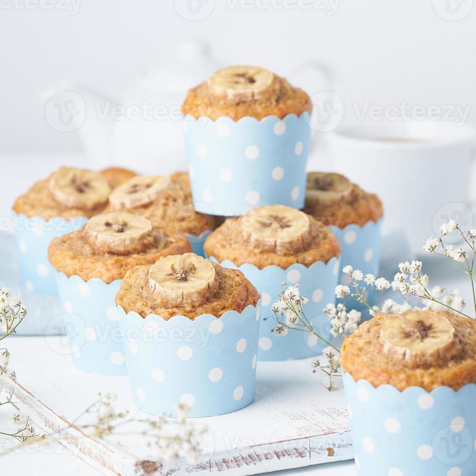 muffin de plátano, pastelitos en papel de cajas de pastel azul, vista lateral. desayuno matutino en blanco foto