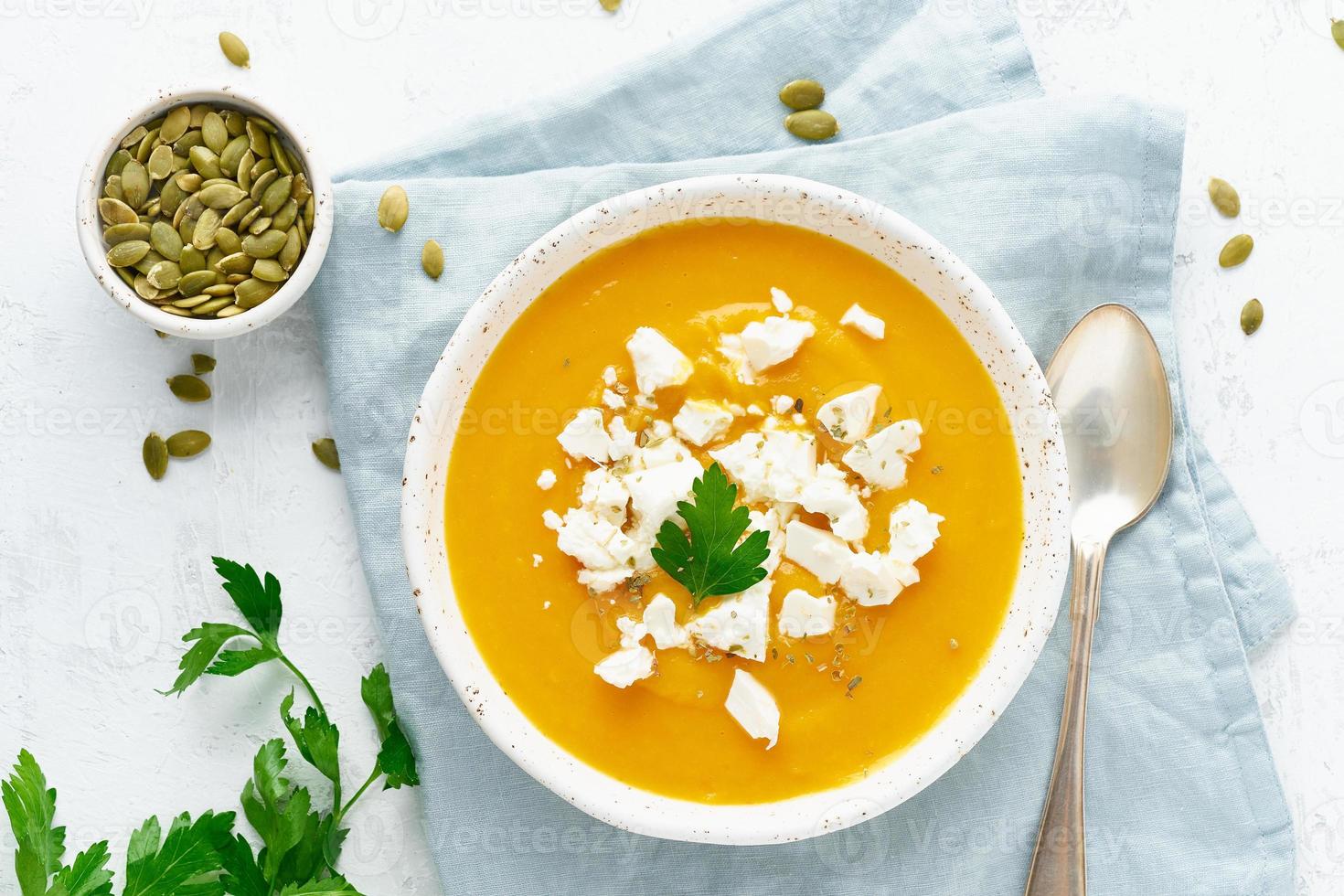 Pumpkin cream soup with feta cheese, autumn homemade food, white background, top view photo