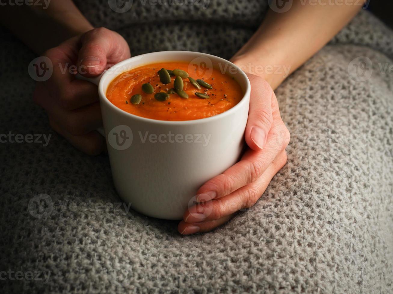 Pupmkin cream soup in hands, dietary vegetarian lunch. Side view. Dark photo. photo