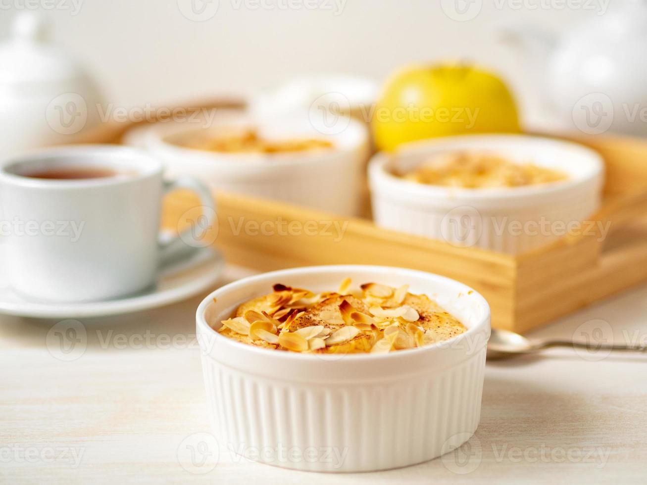 tarta de queso sobre una mesa de madera blanca en la cocina. postre de cuajada delicada con manzanas, hojuelas de almendras foto