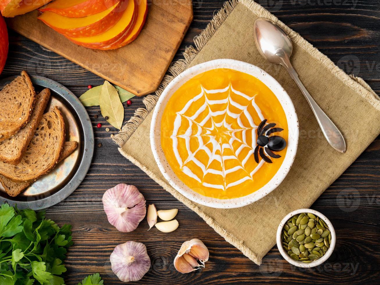 comida divertida para halloween. sopa de puré de calabaza, telaraña, mesa de madera vieja oscura, vista superior. foto