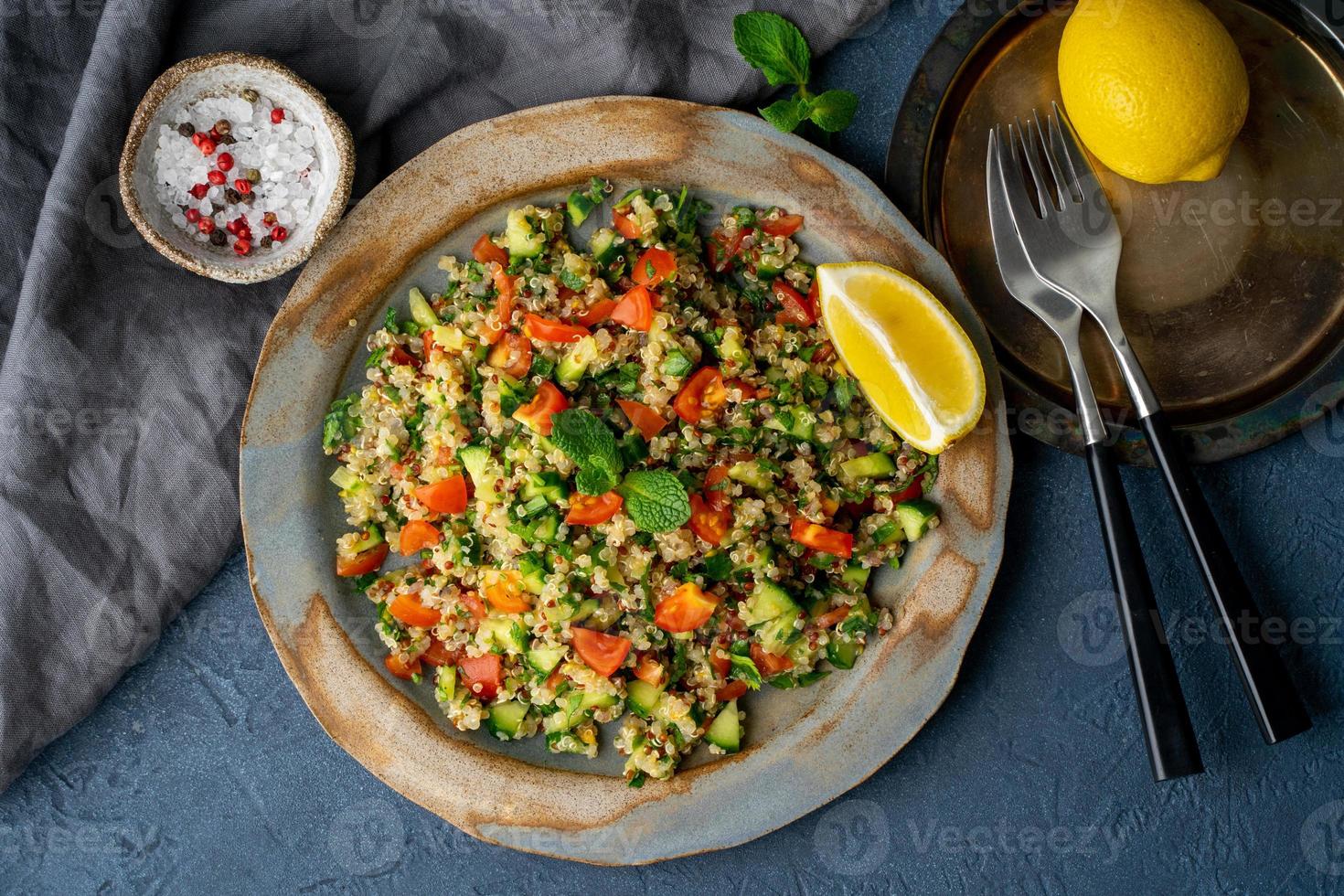 Tabbouleh salad with quinoa. Eastern food with vegetables mix on dark table photo
