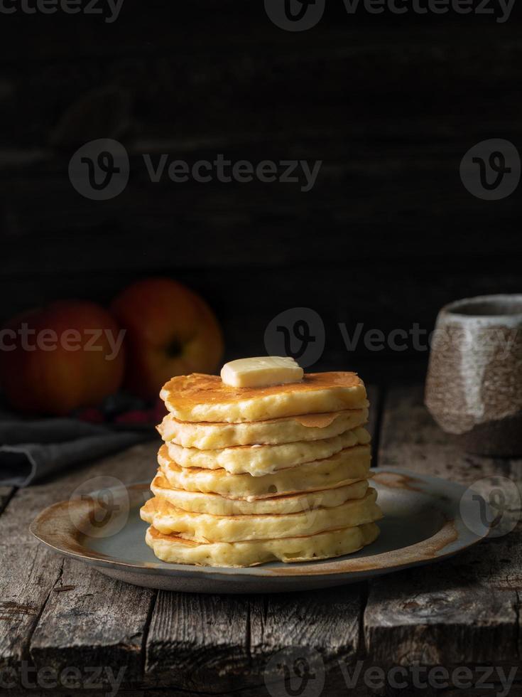 Pancake with butter. Side view, copy space, vertical. Dark moody old rustic wooden background. photo