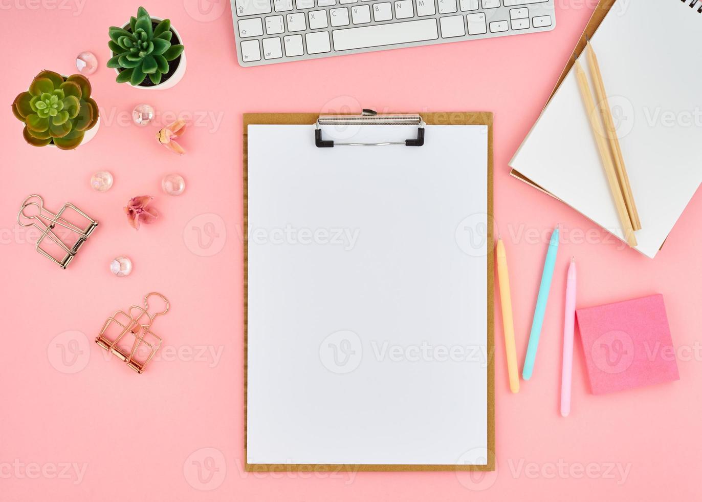 Blank notepad page for text on pink office desktop. Top view of modern bright table with notebook photo