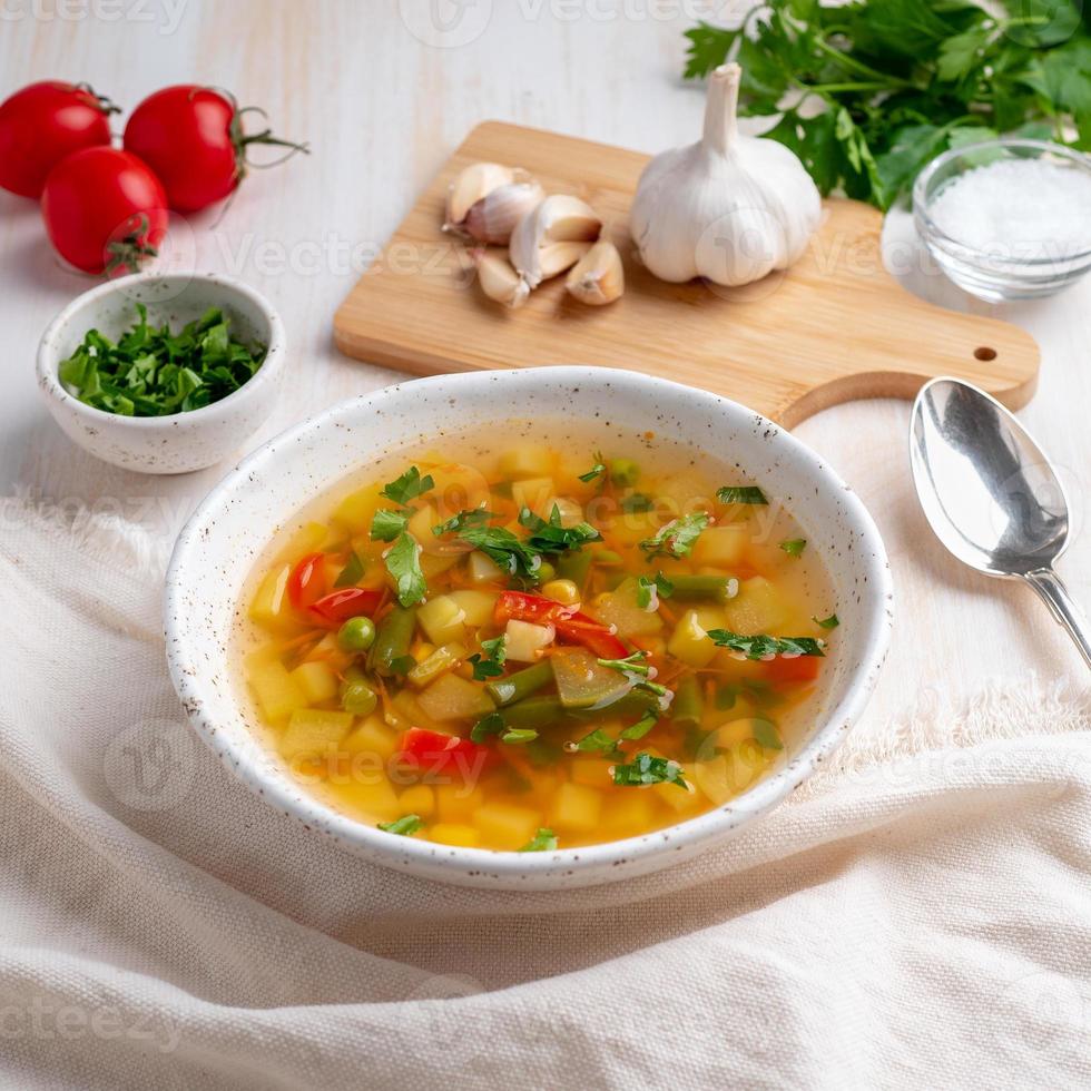 sopa vegetariana dietética de verduras de primavera saludable, fondo de madera blanca, vista lateral, primer plano foto