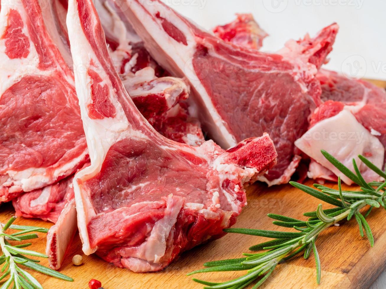Raw lamb ribs on wooden chopping Board on old rustic wooden background, side view photo