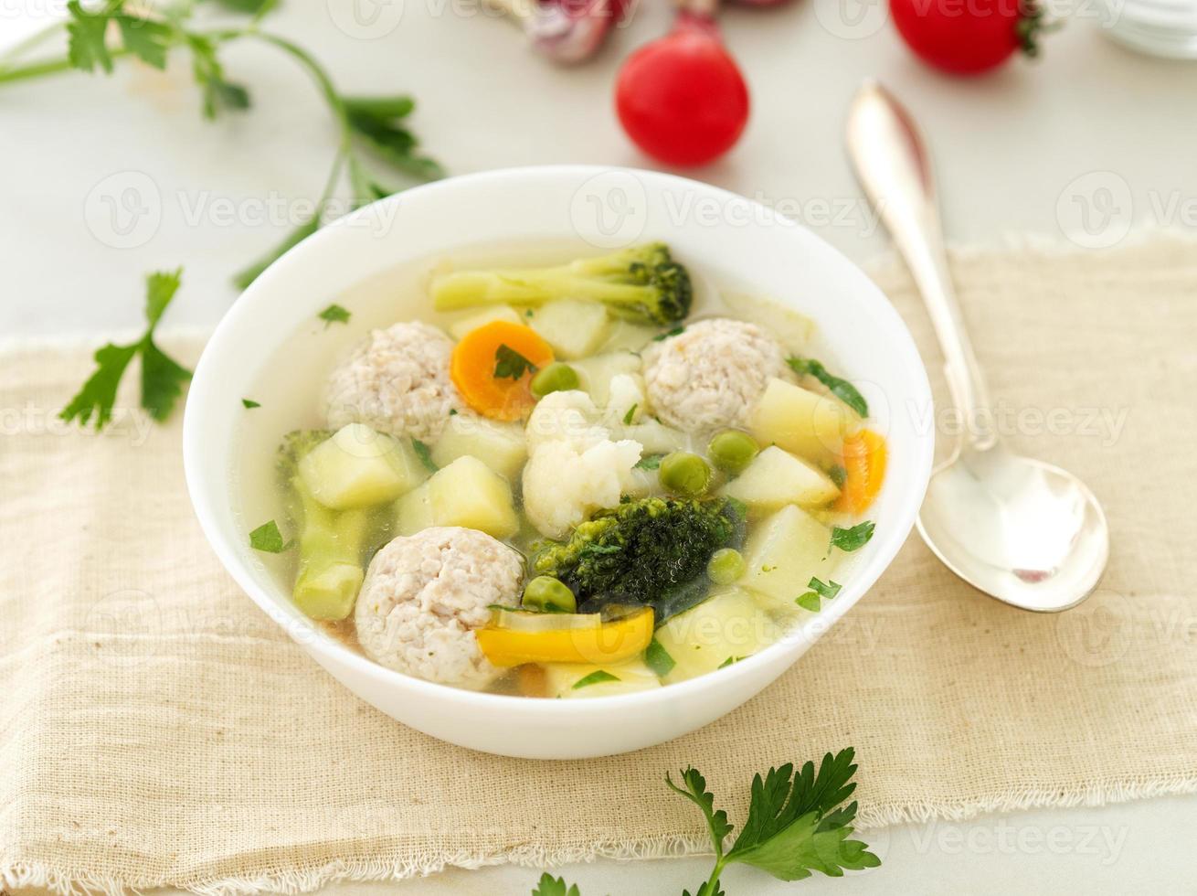 plato de sopa, una taza de caldo y verduras, albóndigas de pavo y pollo, vista lateral foto