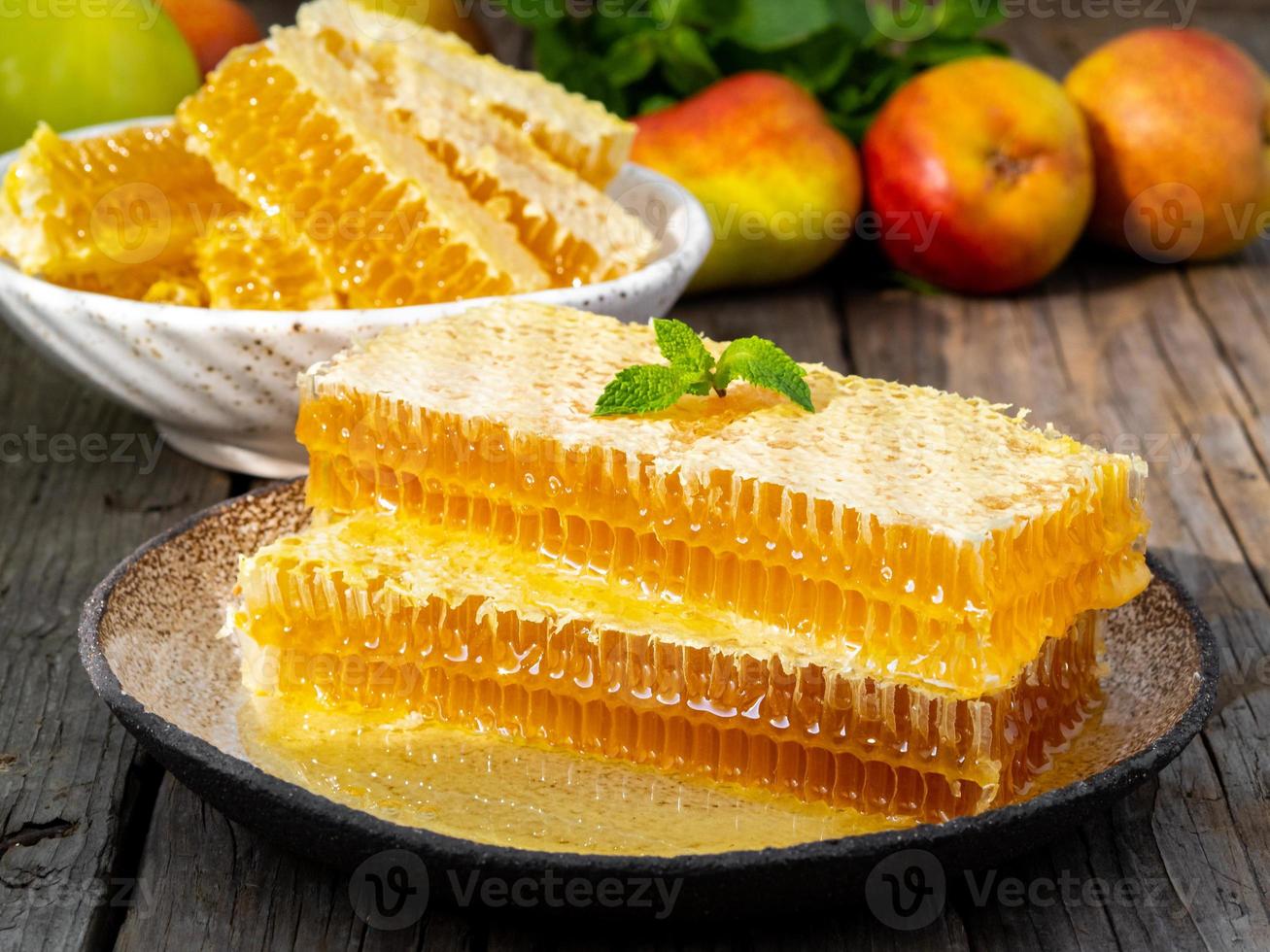 honey in honeycomb, close-up, on white ceramic plate, on wooden rustic table, side view, sunlight photo