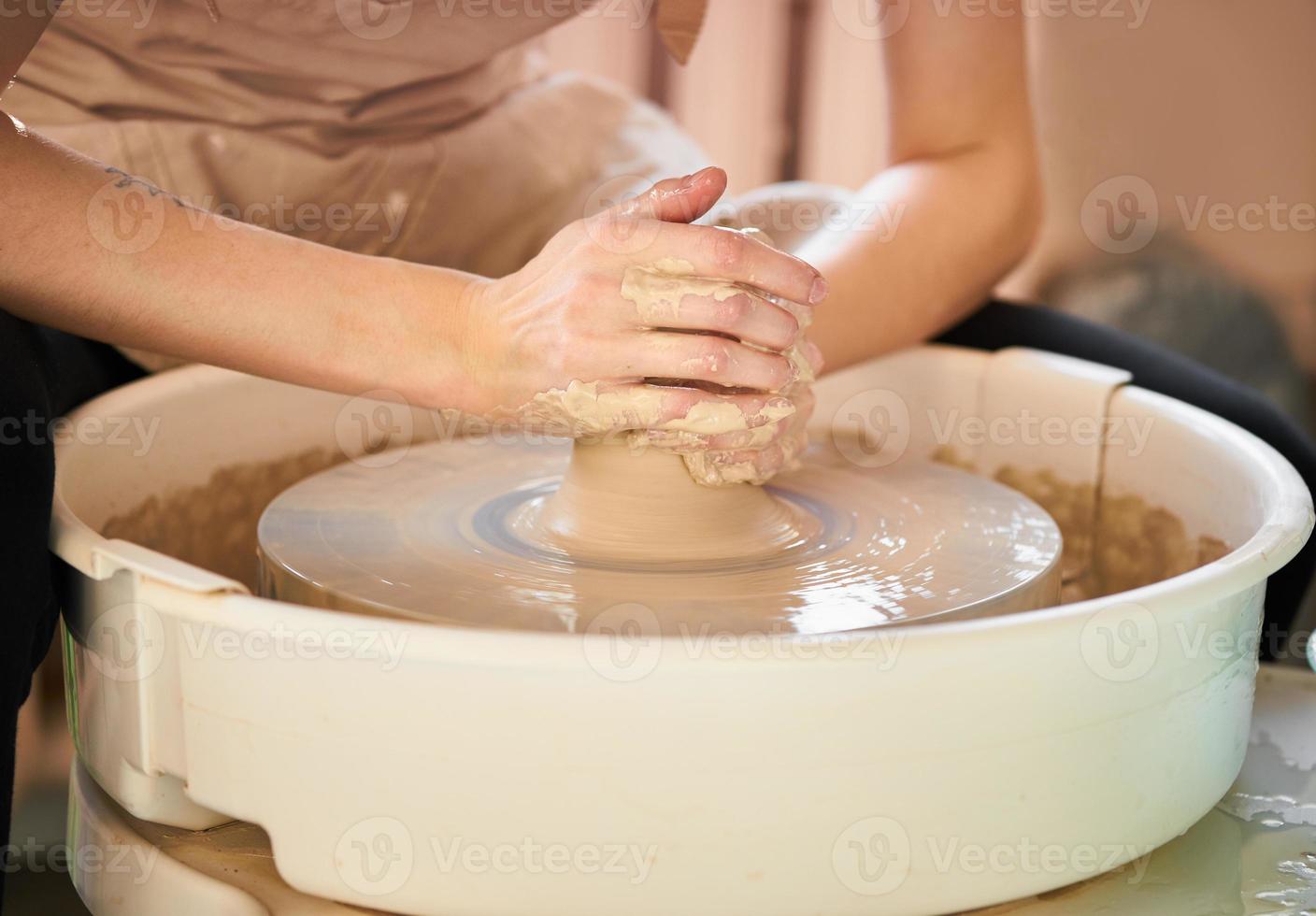 Woman making ceramic pottery on wheel, hands close-up, creation of ceramic ware photo