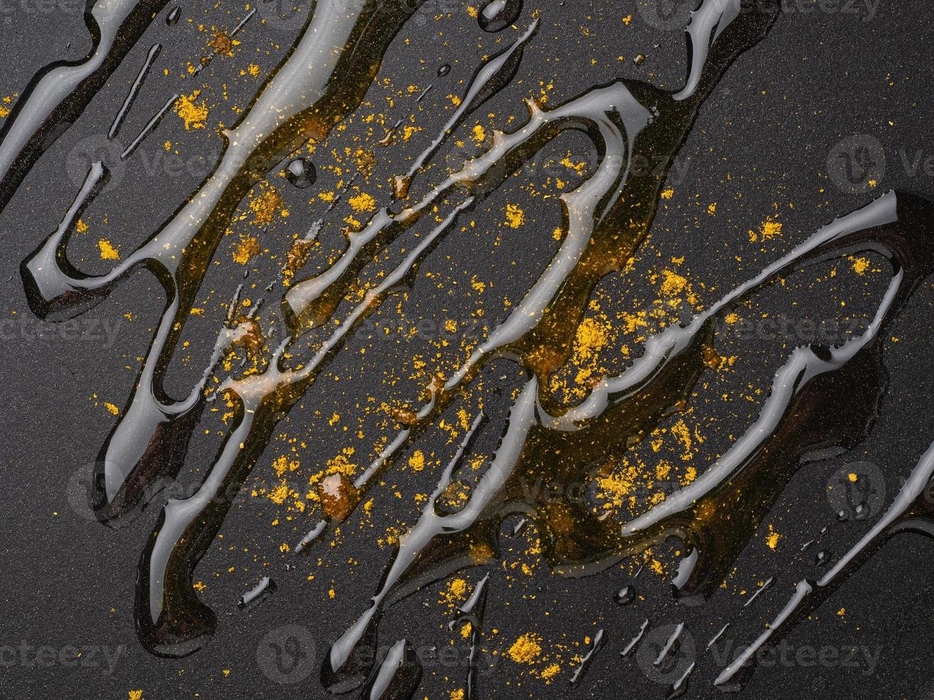 Dark food background with curry spices and oil on fluoroplastic frying pan, macro, close-up photo