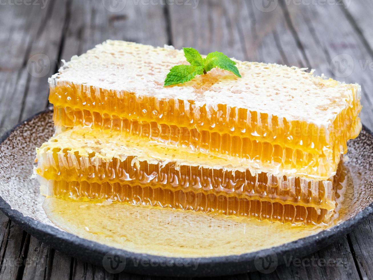 honey in honeycomb, close-up, on white ceramic plate, on wooden rustic table, side view, sunlight photo