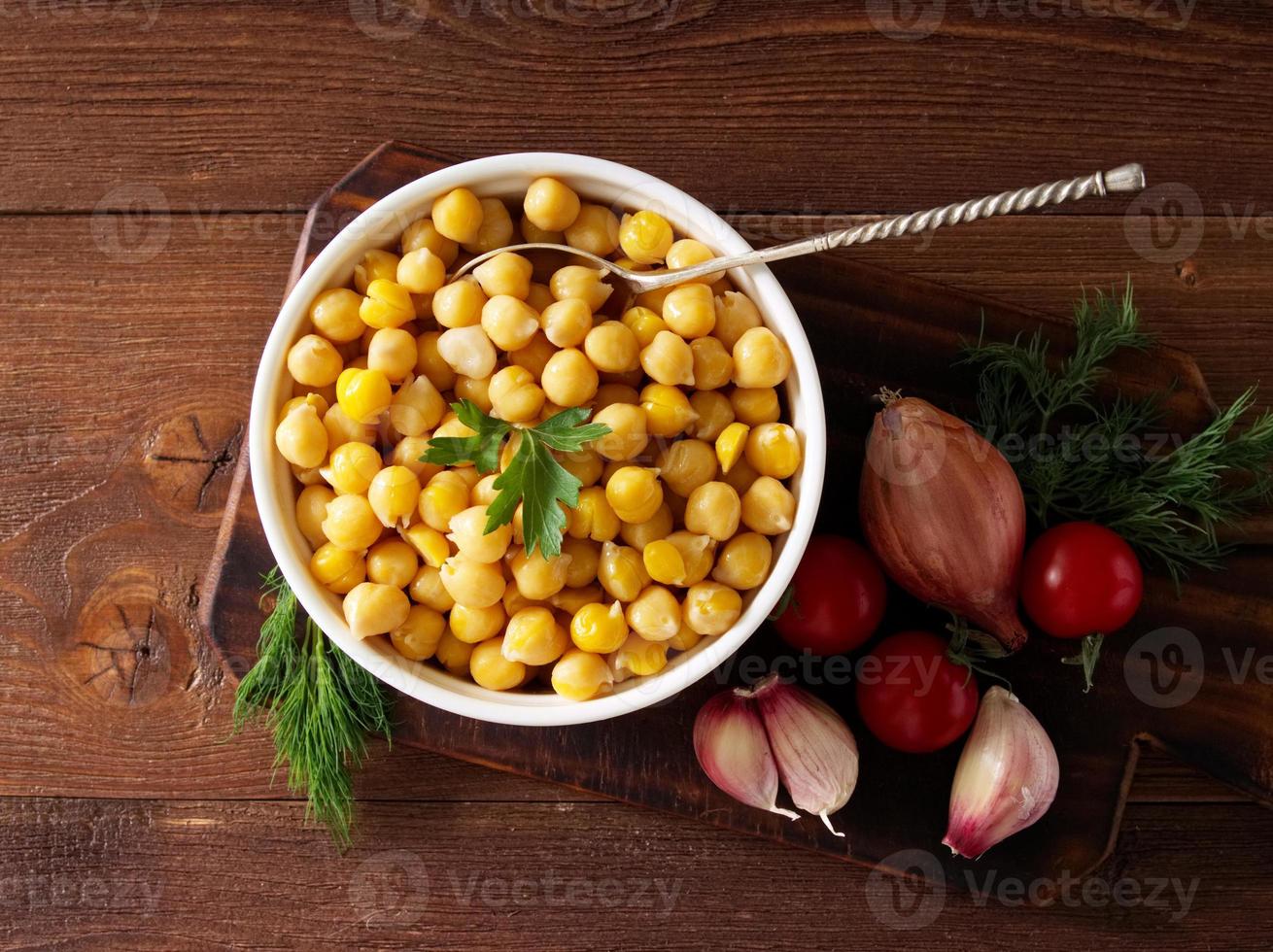 garbanzos cocidos en un tazón sobre una mesa de madera oscura. alimento proteico saludable, vegetariano y nutritivo de oriente medio. vista superior. foto