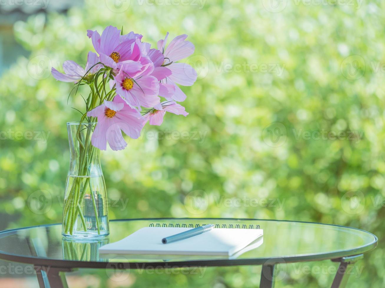 cuaderno, bolígrafo sobre la mesa en el jardín del parque, ramo de flores, espacio vacío. concepto para pensar foto