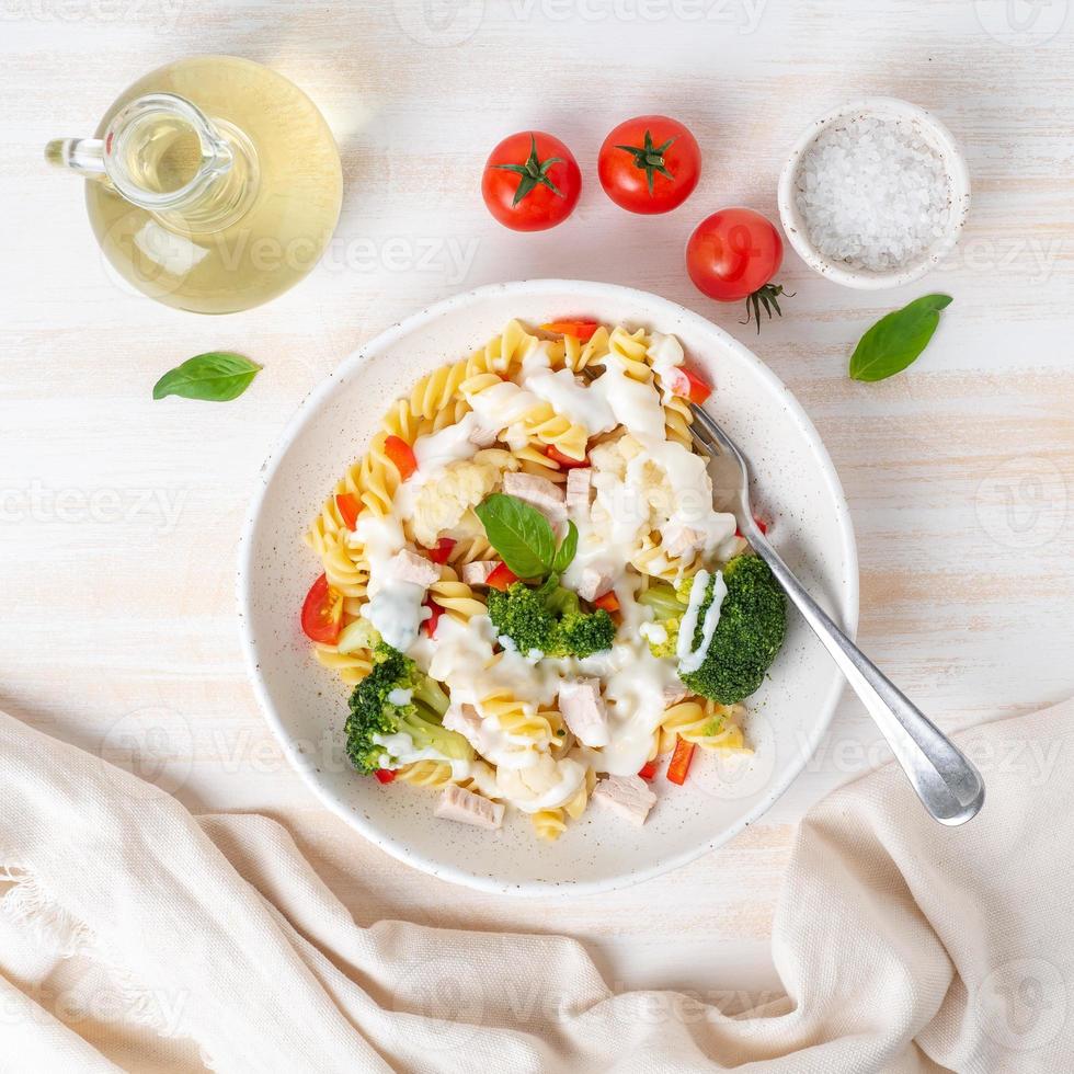 fusilli de pasta con verduras, carne hervida al vapor, salsa blanca sobre una mesa de madera blanca, alimentos bajos en calorías, dieta baja en grasas, vista superior foto