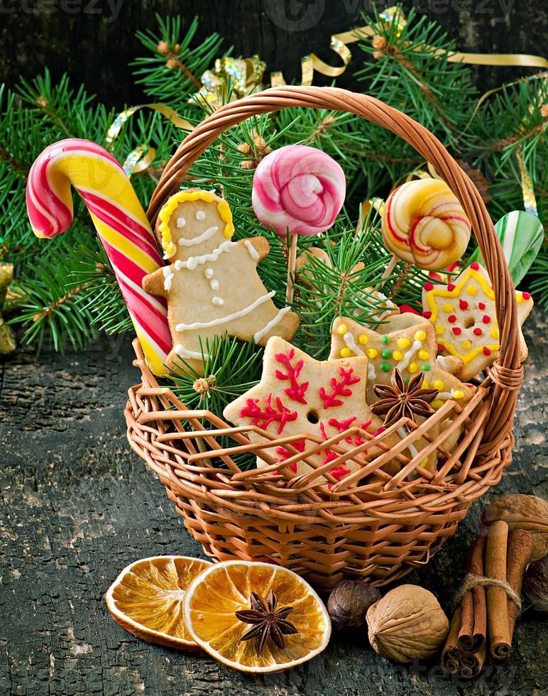 galletas de jengibre de navidad y piruletas en una canasta sobre fondo de madera vieja foto