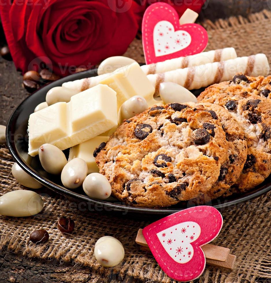 White chocolate, almonds and cookies on a wooden background photo
