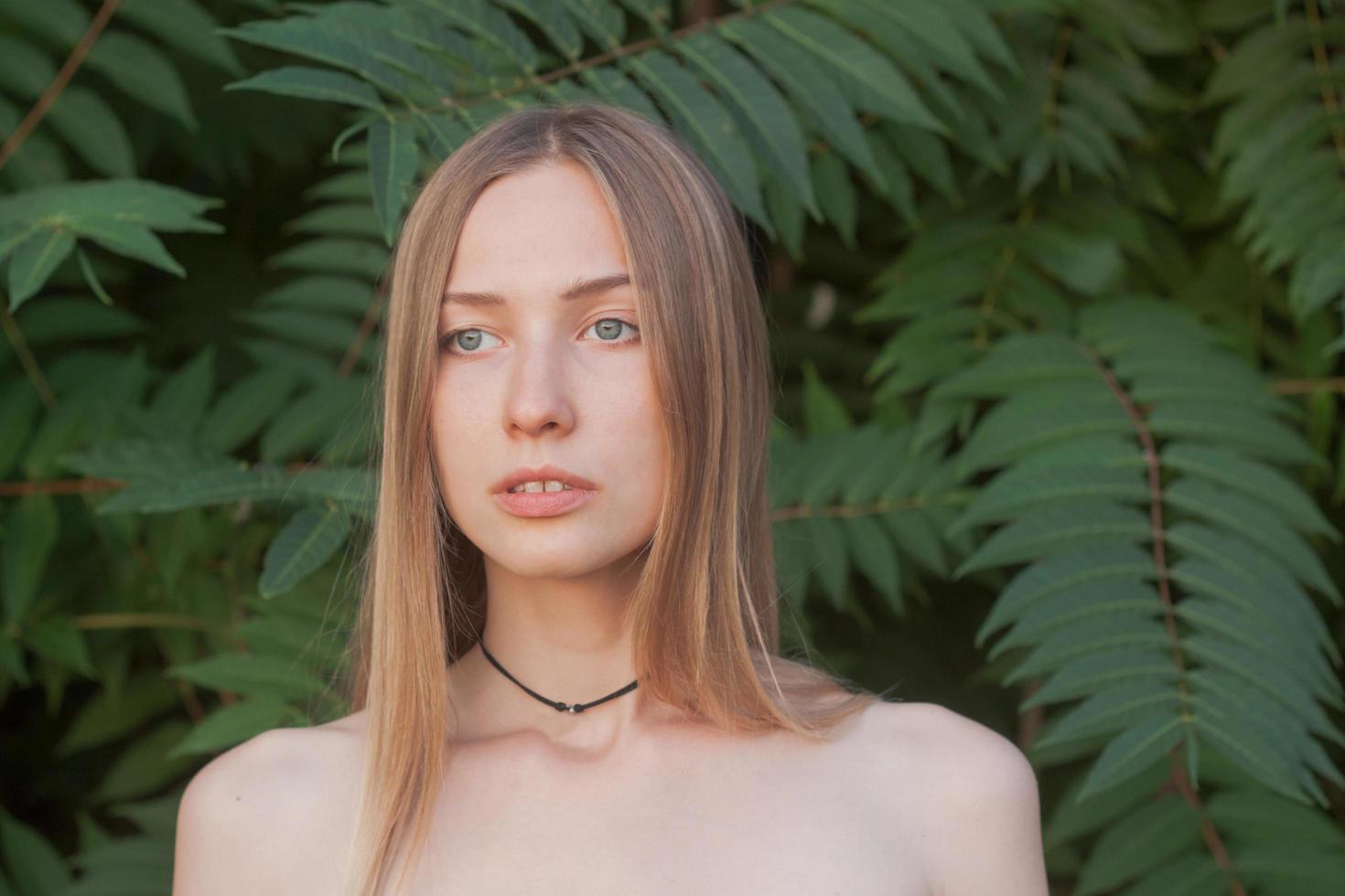 retrato de una bella joven con hojas verdes, una bella dama rubia con arbustos de primavera foto