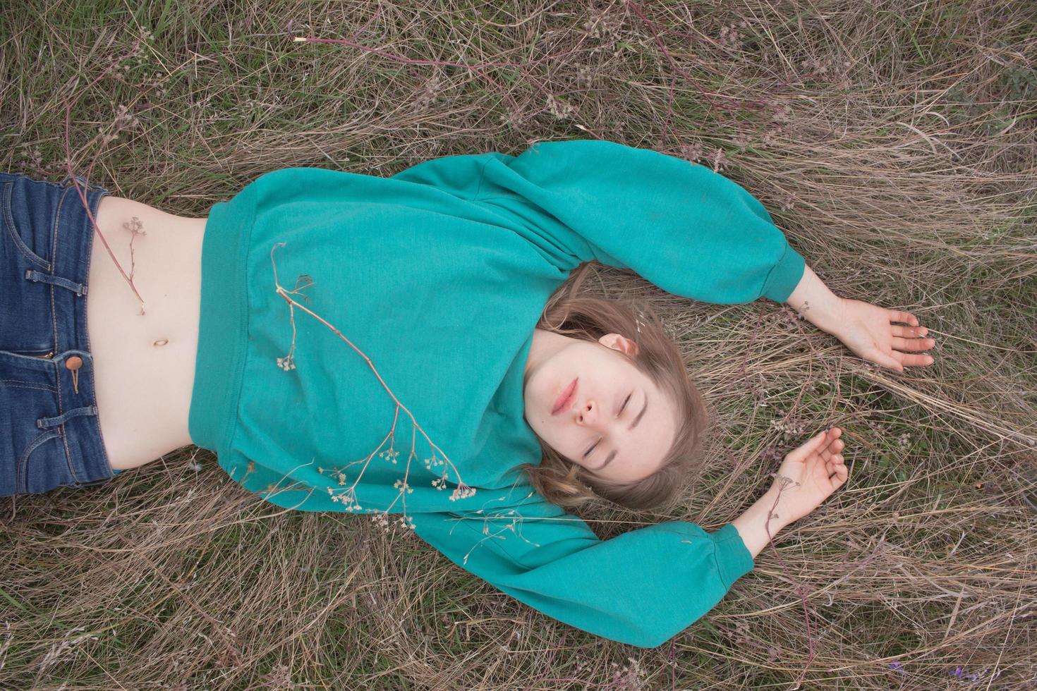 mujer joven en los campos, retrato de una mujer hermosa relajándose en la hierba seca foto