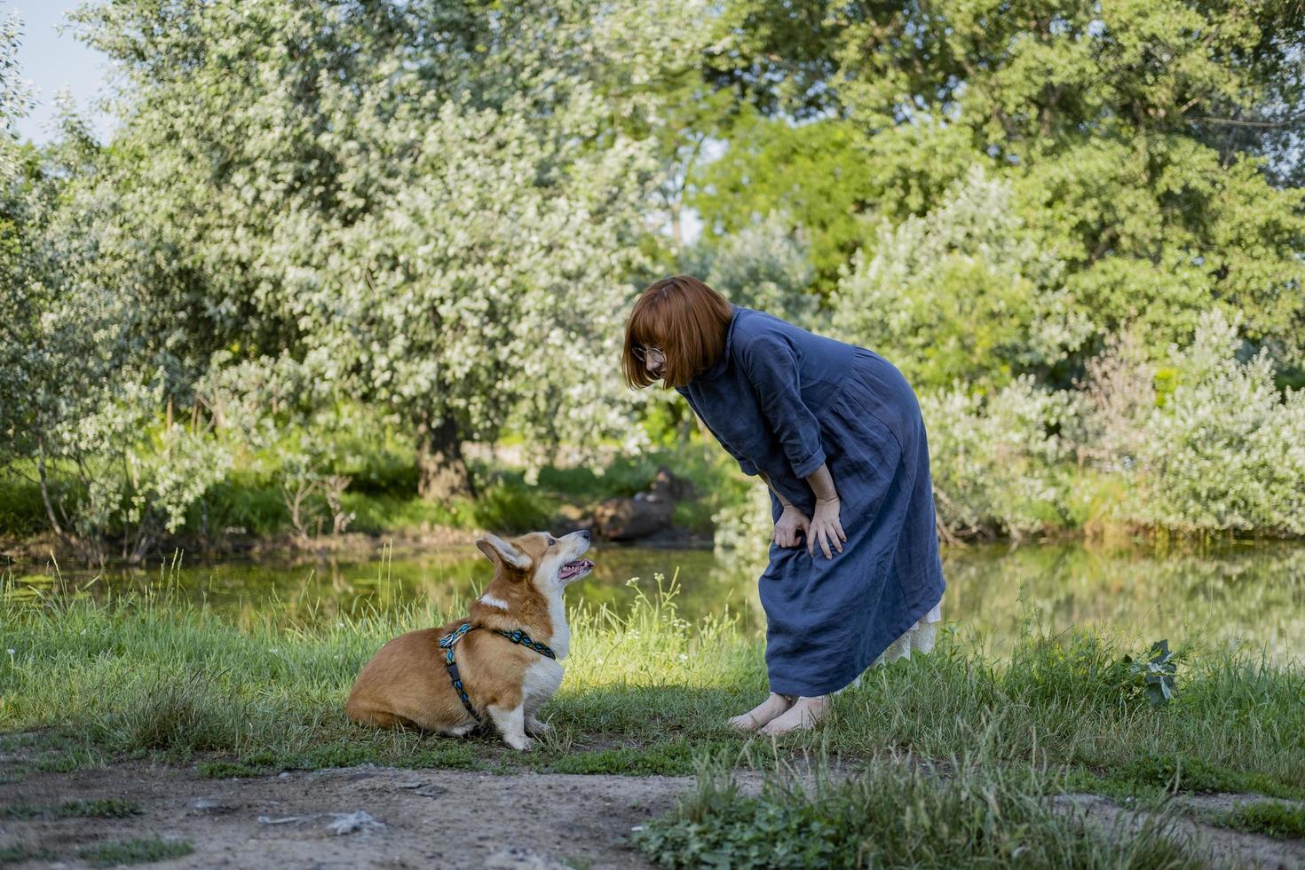 oung woman in retro dress with funny corgi dog on the picnic photo