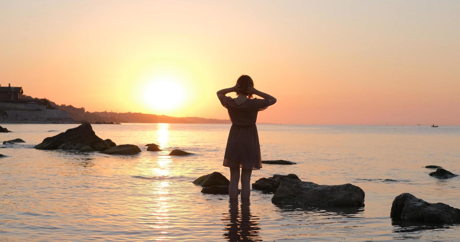 Young woman in dress relaxing on the summer beach during beautiful sunrise photo