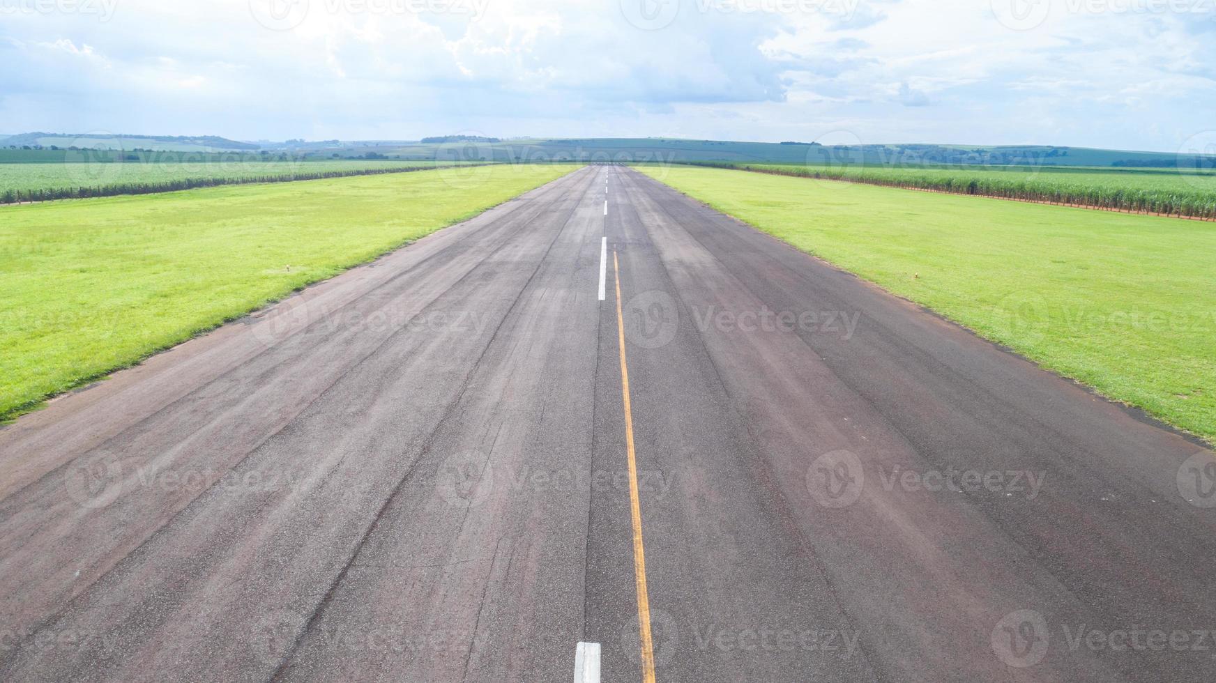 Aerial view of paved airplane runway on Brazil. Small propeller airplanes remote airstrip with Sugar Cane plantation in background. photo