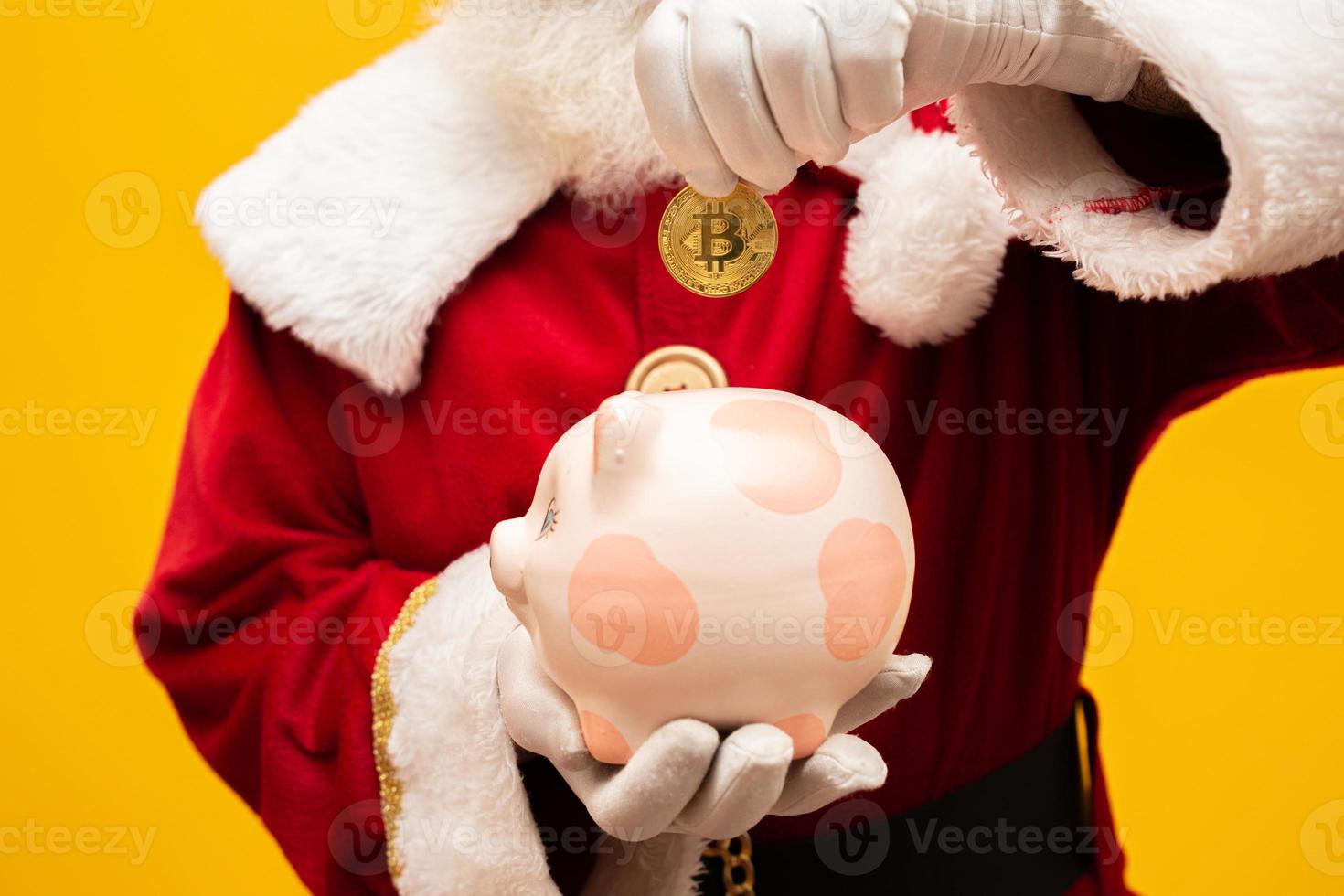 santa claus poniendo monedas en una alcancía de cerámica. concepto de ahorro para fin de año. gastar en navidad. gastado en regalos de navidad. foto