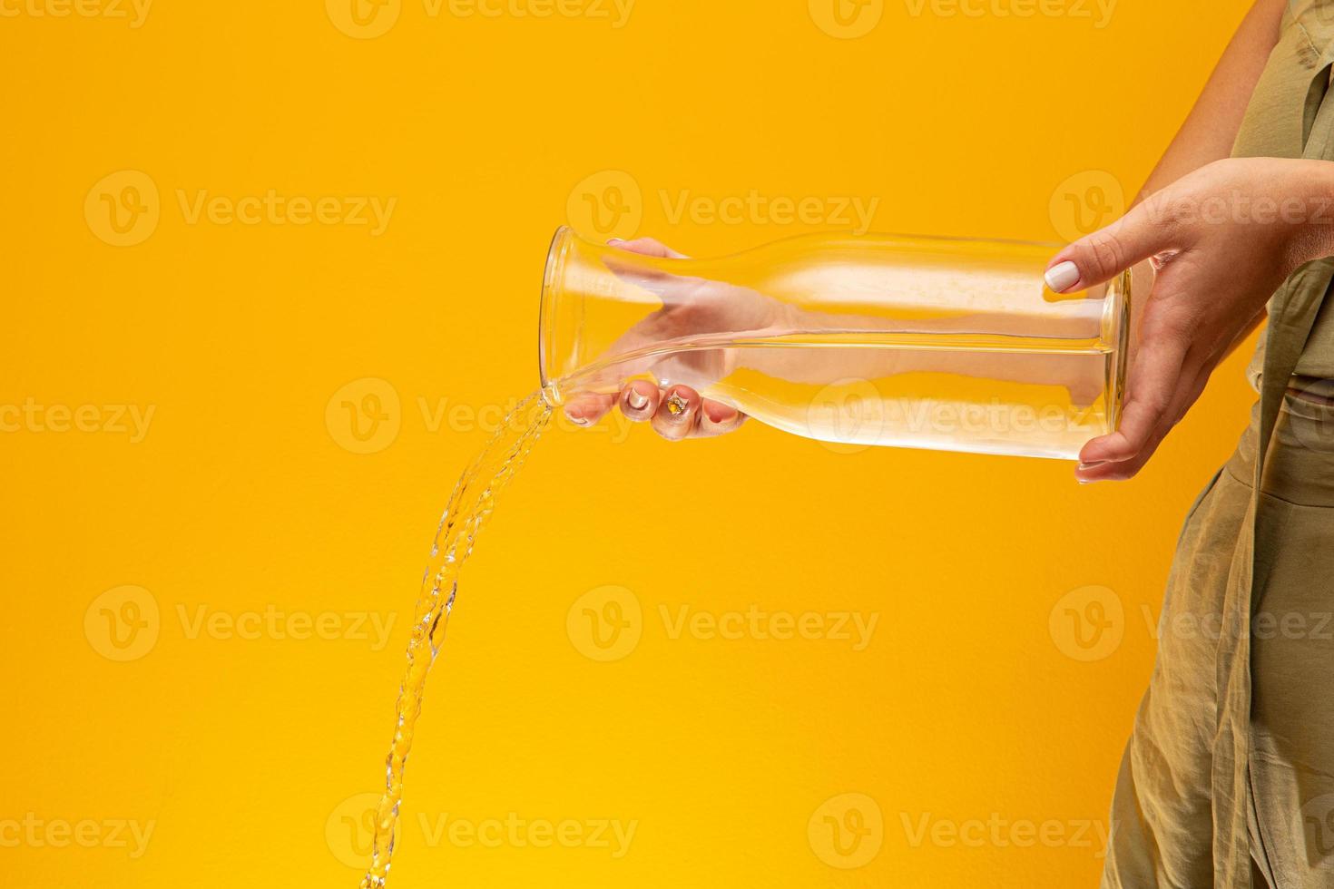 Water Pour into Glass. Water pouring. Splashing water on yellow background. photo