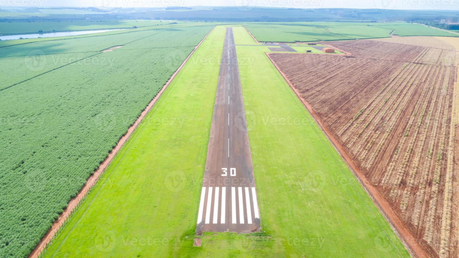 Aerial view of paved airplane runway on Brazil. Small propeller airplanes remote airstrip with Sugar Cane plantation in background. photo