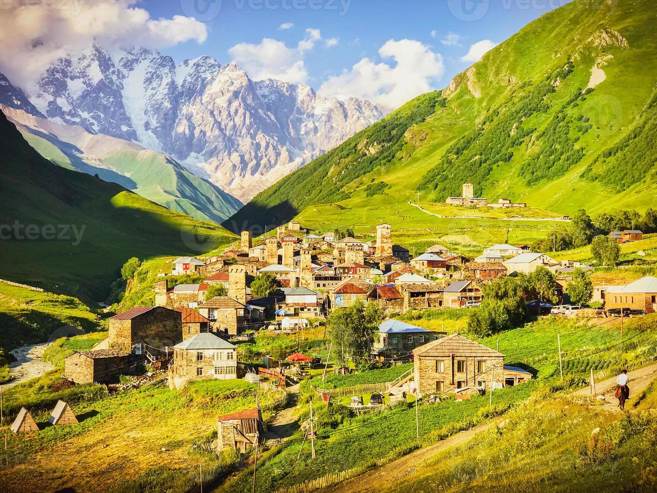 Square image of dramatic Ushguli village panorama during the sunset with horse rider in the foreground and caucasus mountains in the background photo