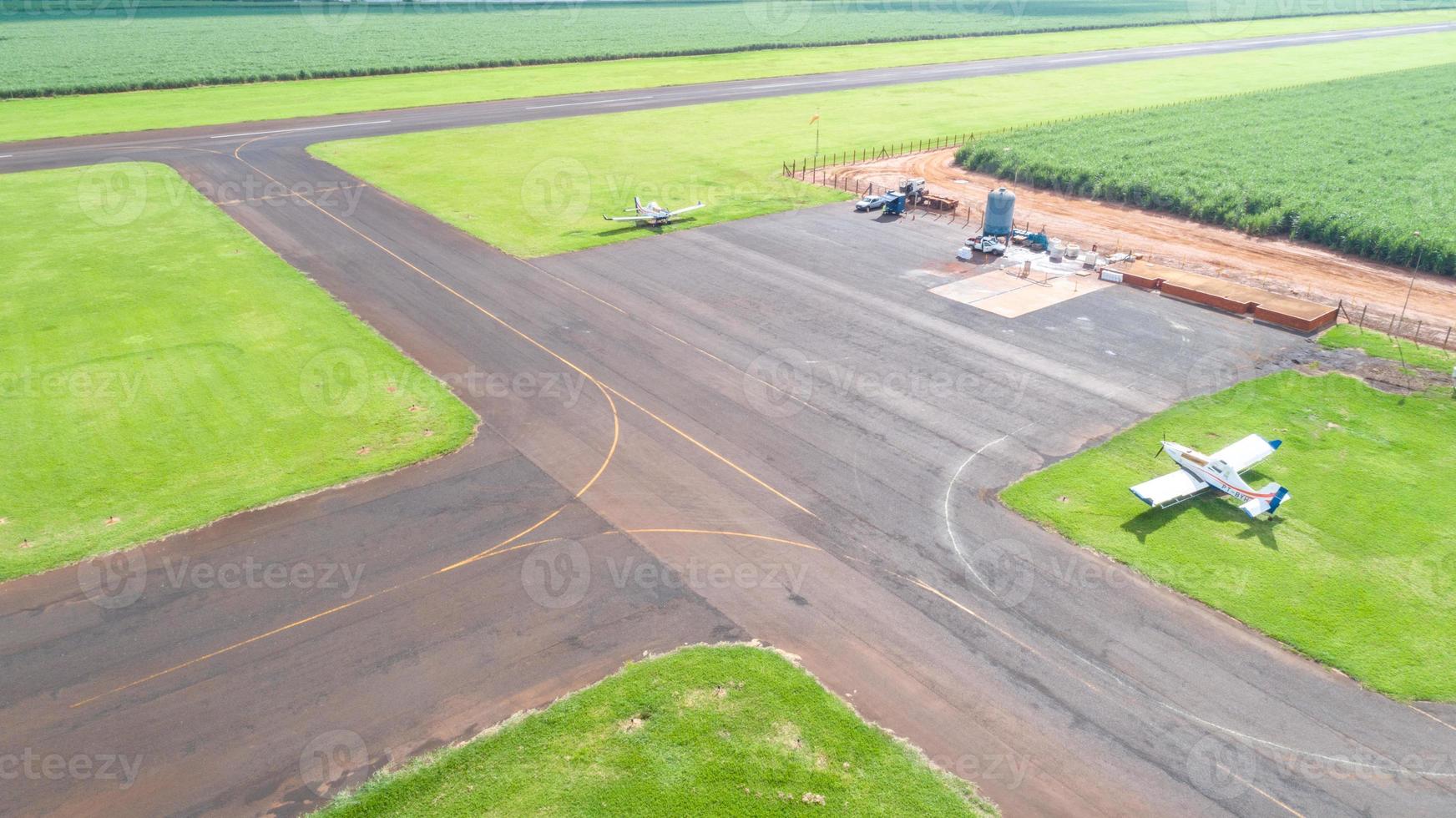 vista aérea de la pista de aterrizaje pavimentada del avión en brasil. pequeños aviones de hélice pista de aterrizaje remota con plantaciones de caña de azúcar en el fondo. foto