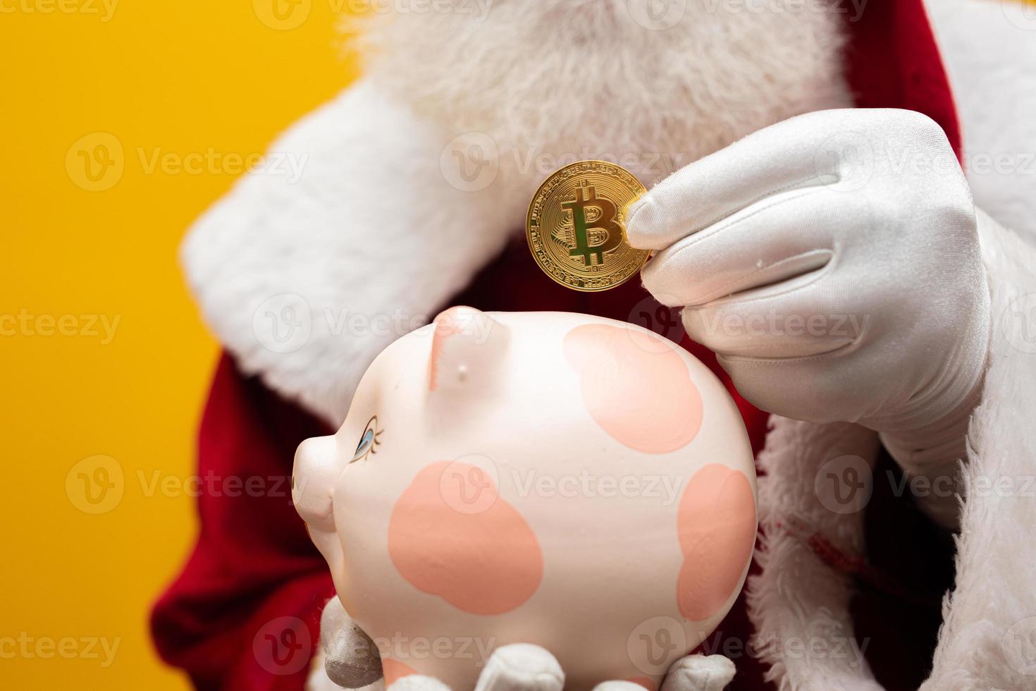 santa claus poniendo monedas en una alcancía de cerámica. concepto de ahorro para fin de año. gastar en navidad. gastado en regalos de navidad. foto