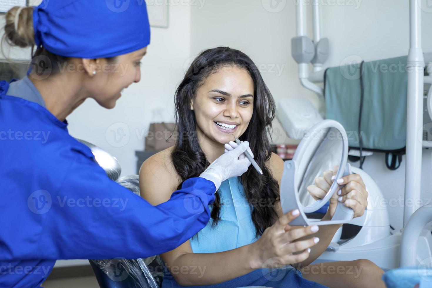 Beautiful woman checking her teeth after treatment. photo