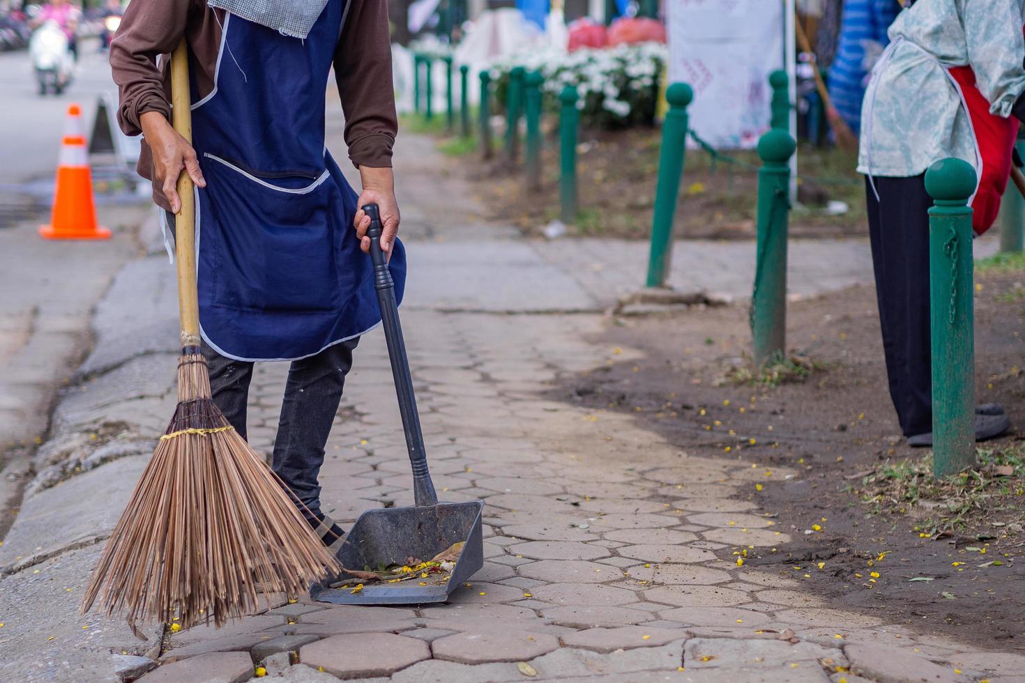 Young woman swept garbage by broom. photo