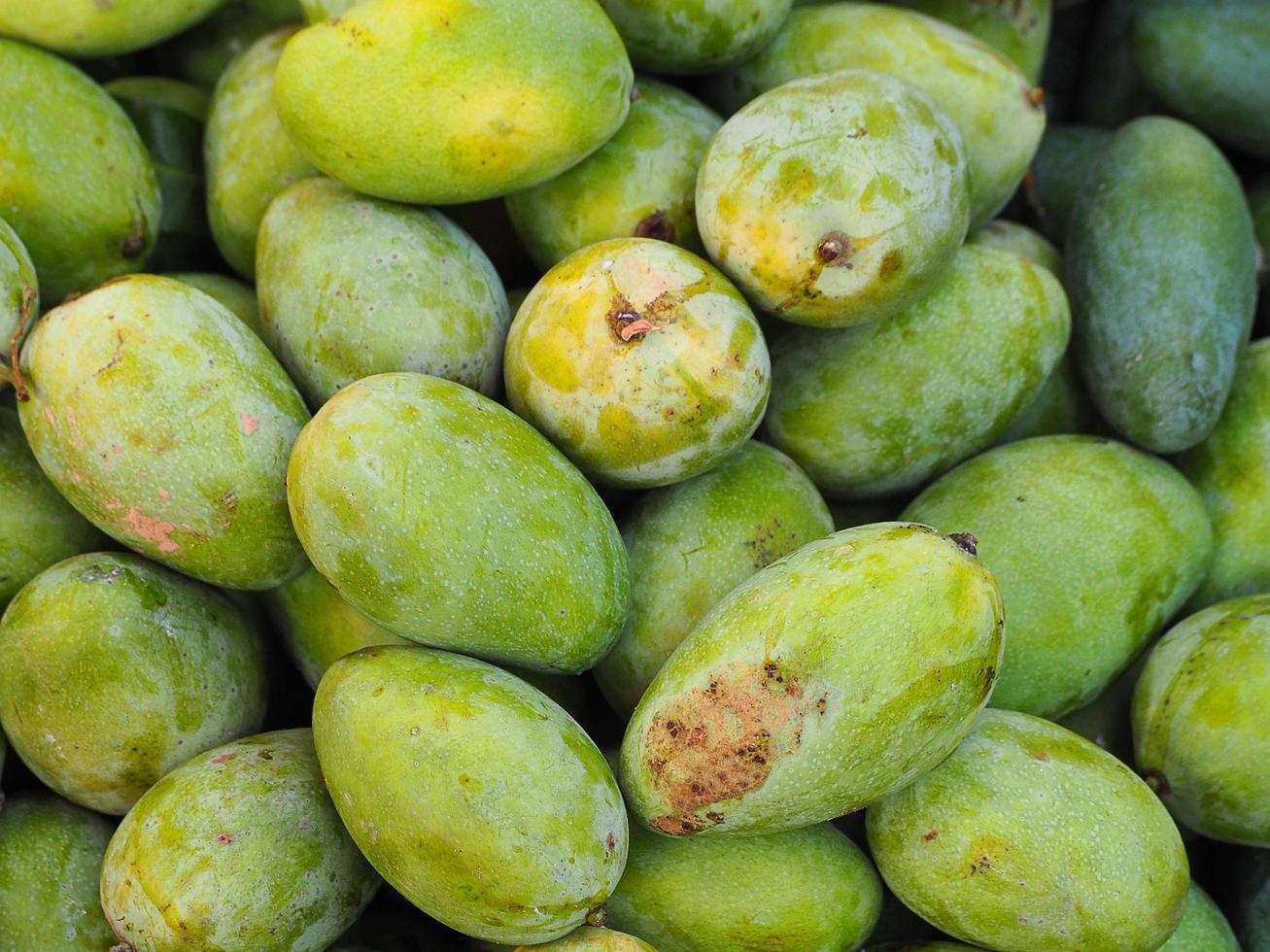 pila de mango verde fresco a la venta en el mercado foto