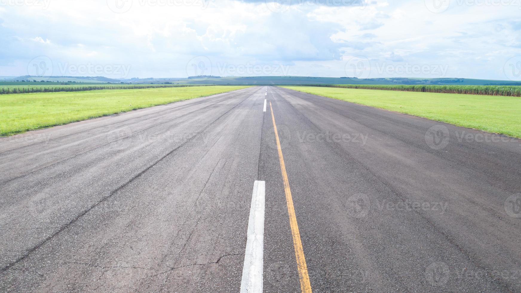 vista aérea de la pista de aterrizaje pavimentada del avión en brasil. pequeños aviones de hélice pista de aterrizaje remota con plantaciones de caña de azúcar en el fondo. foto